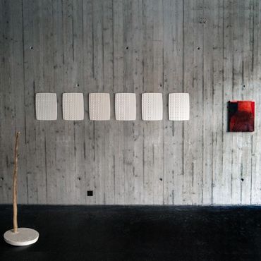 Plaster casts on a concrete wall, with a red painting and a sculpture amde with wood and plaster
