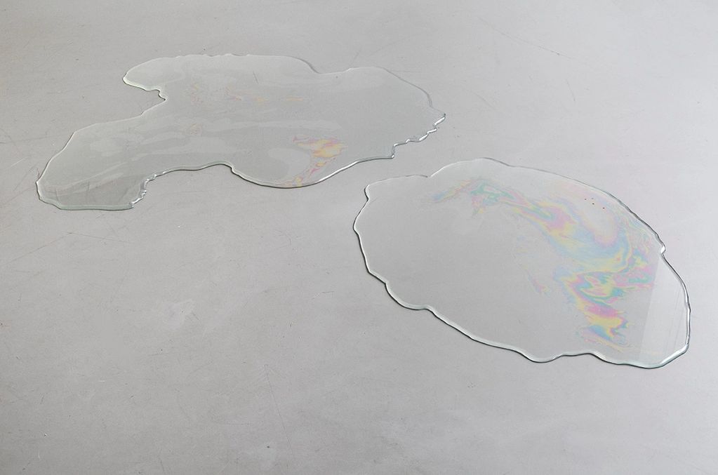 Irregular glass shapes on a gray surface.