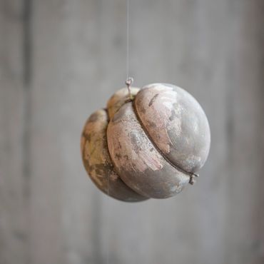 Painted and sculpted balls hanging in front of concrete wall