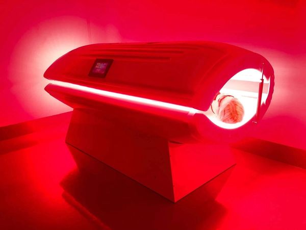 Person inside a red-lit tanning bed.