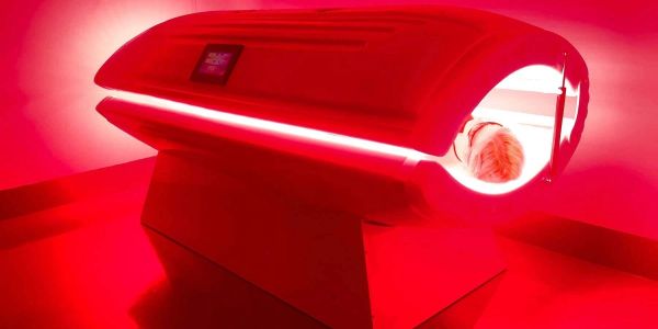 Person inside a red-lit tanning bed.