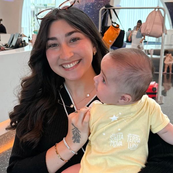 Smiling woman holding a baby in a bright indoor setting.