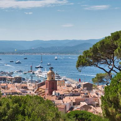 Aerial view of Saint-Tropez with italian tile rooftops along the ocean and yachts off shore
