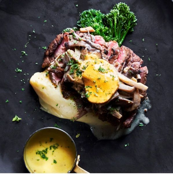A black plate with meat, cheese, and veggies