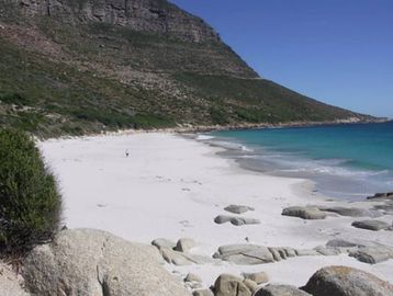 Large white sandy beach next to ocean with large green mountain