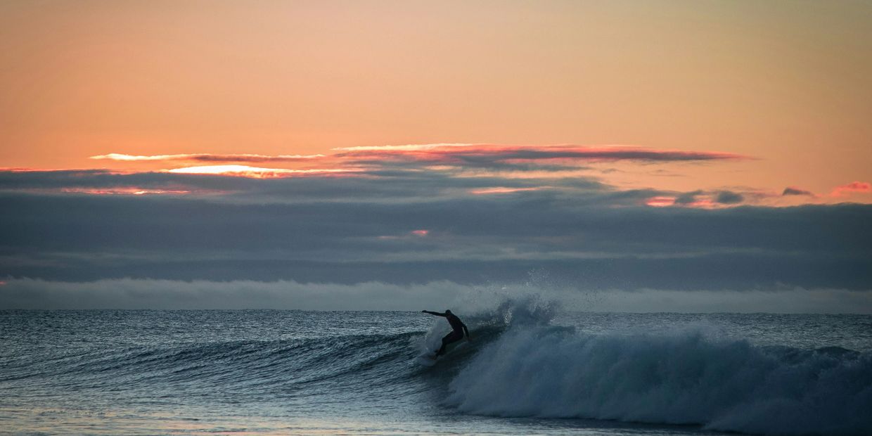 Picture of one surfer on a wave at sunset