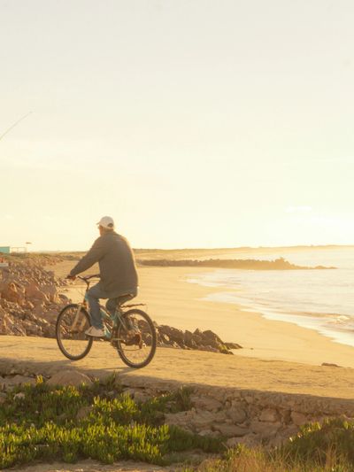 Man riding bicycle along the beach at sunset
