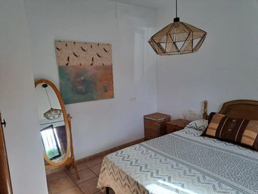 Cozy bedroom with wooden furniture and geometric pendant light.