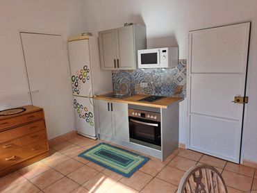 Compact kitchen with wooden countertop, colorful tile backsplash, and decorated fridge.