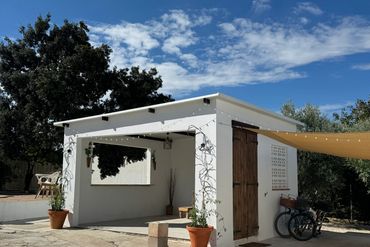 White outdoor pavilion with string lights and bicycles under a yellow canopy.