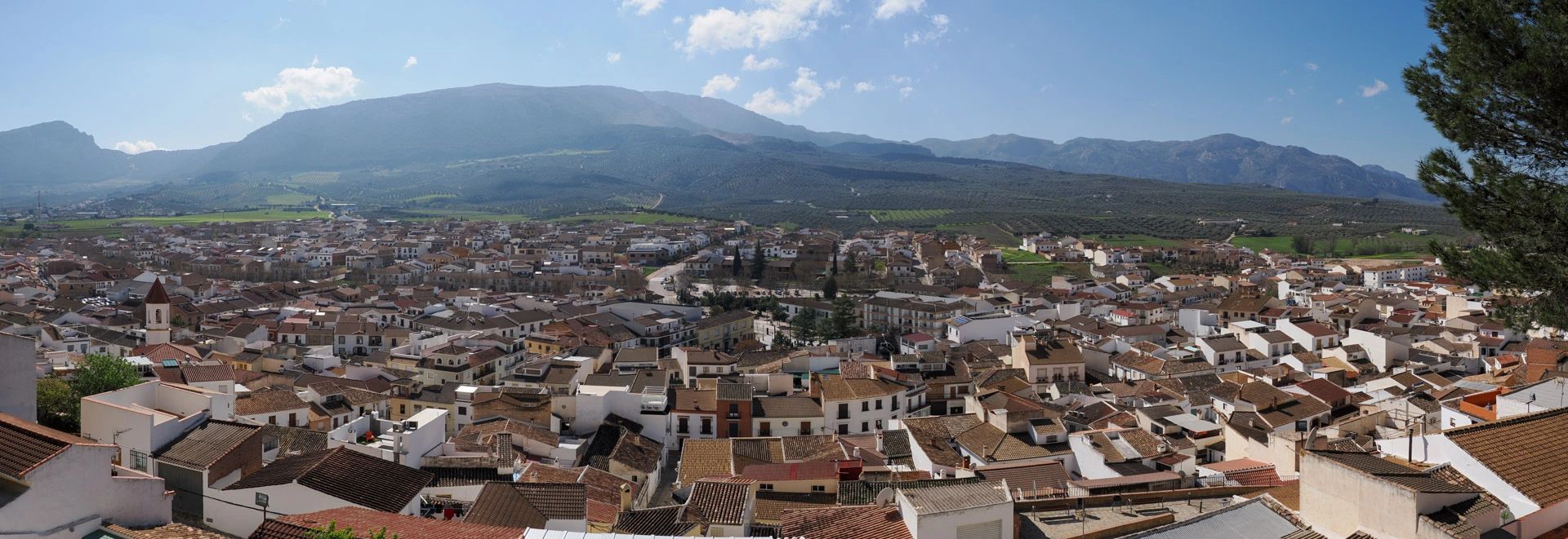 Panoramic view of a town with mountains in the background under a clear blue sky.