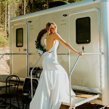 bride looking over her shoulder as she climbs the stairs of a luxury restroom trailer
