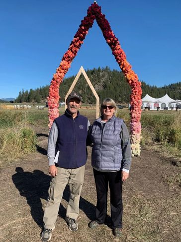 A man and woman smiling in front of a wedding ceremony arch