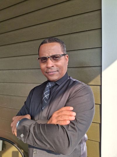 Confident man in glasses and tie standing with arms crossed.