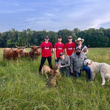 Farm family posing with dogs and scottish highland cattle