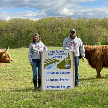 Farmers with environmentally verified sign and highland cows