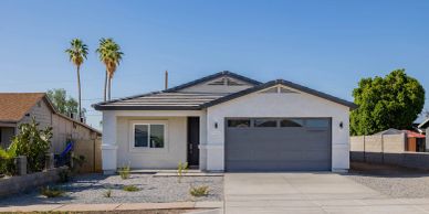 Single-story white house with a two-car garage and palm trees.