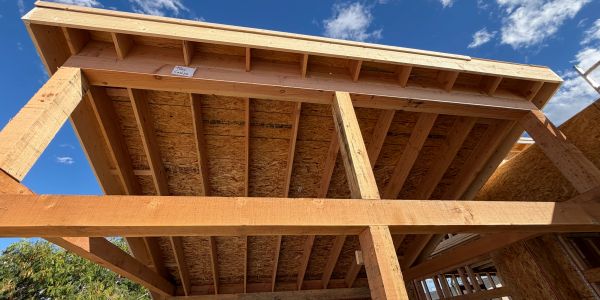 Underside view of wooden house framing under construction.