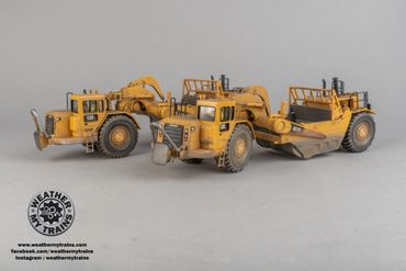 Two detailed yellow construction vehicle models on a gray surface.