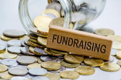 Coins spilled from a jar with a fundraising block.