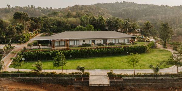 A modern single-story house surrounded by greenery and hills.