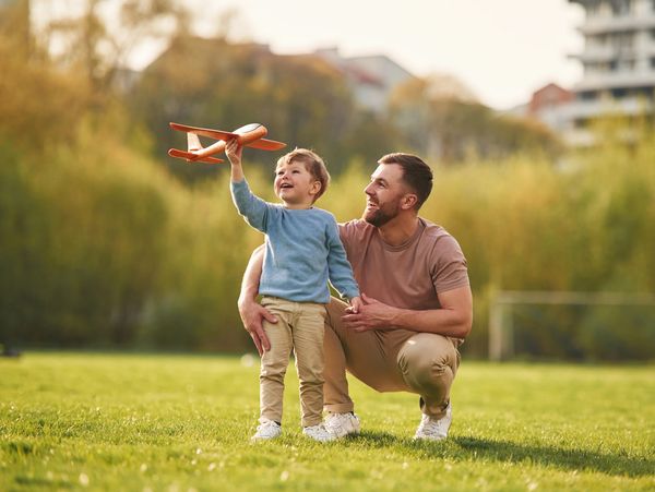 Happy father with son are having fun on the field at summertime.