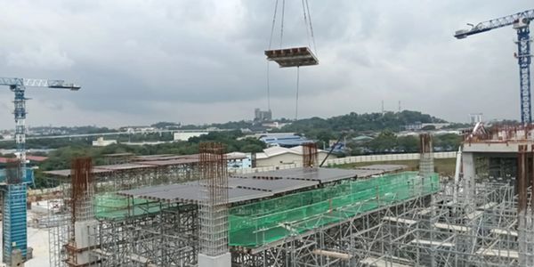 Construction site with cranes and scaffolding under a cloudy sky.