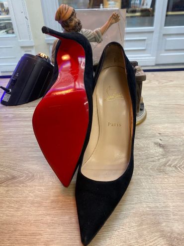 Pair of black Christian Louboutin high heels with signature red soles.