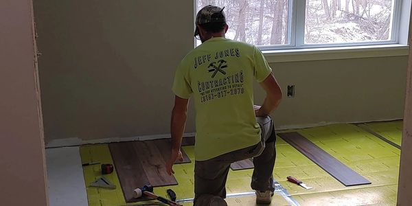 Worker installing wood flooring indoors.
