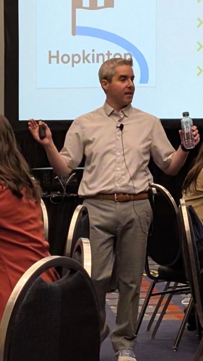 Man speaking in front of a presentation screen.