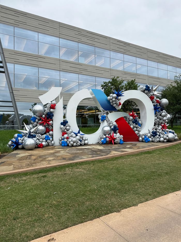 Decorated large '100' sculpture outdoors with balloons.