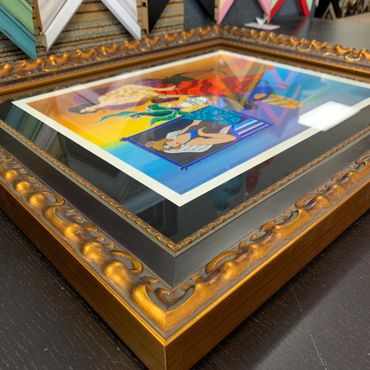 Ornate golden frame with colorful artwork inside on a black surface.