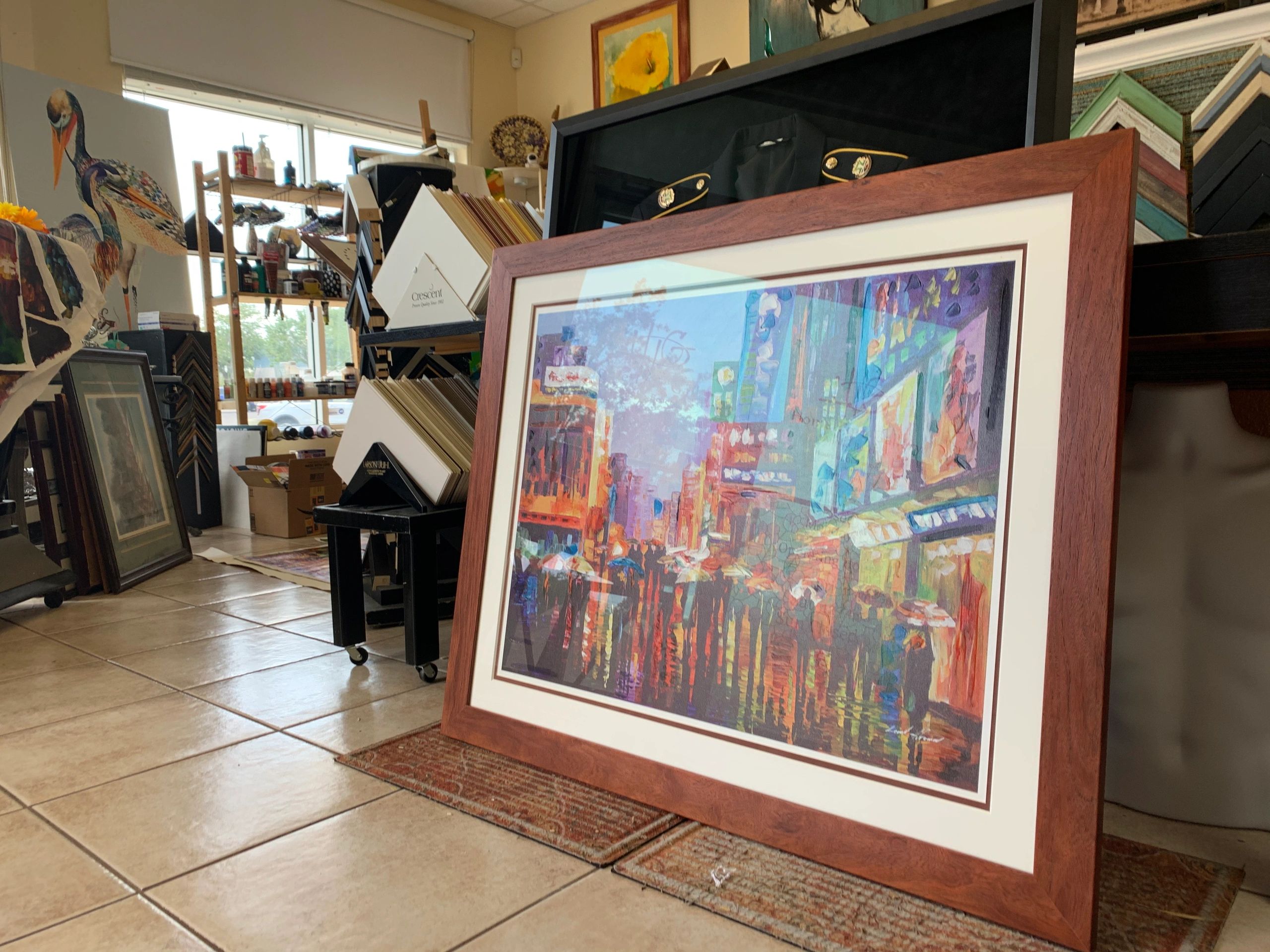 Framed colorful cityscape painting leaning on the floor in an art shop.