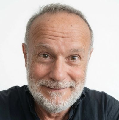 Smiling elderly man with a white beard and black shirt.