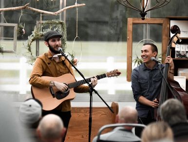 Two musicians perform live, one with a guitar and the other with a double bass.