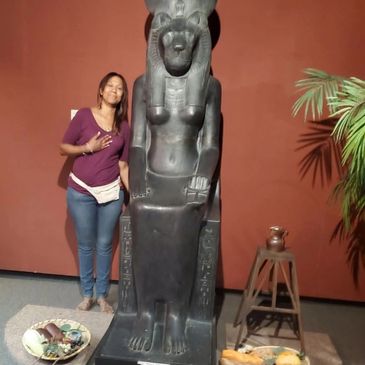 Woman posing next to an ancient Egyptian statue.