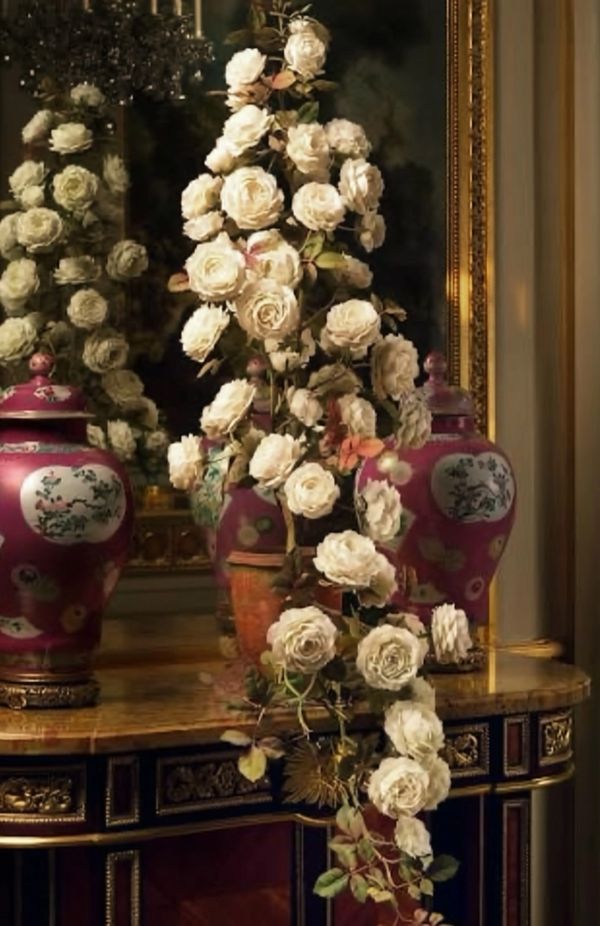 White roses cascading over an ornate table with decorative vases.