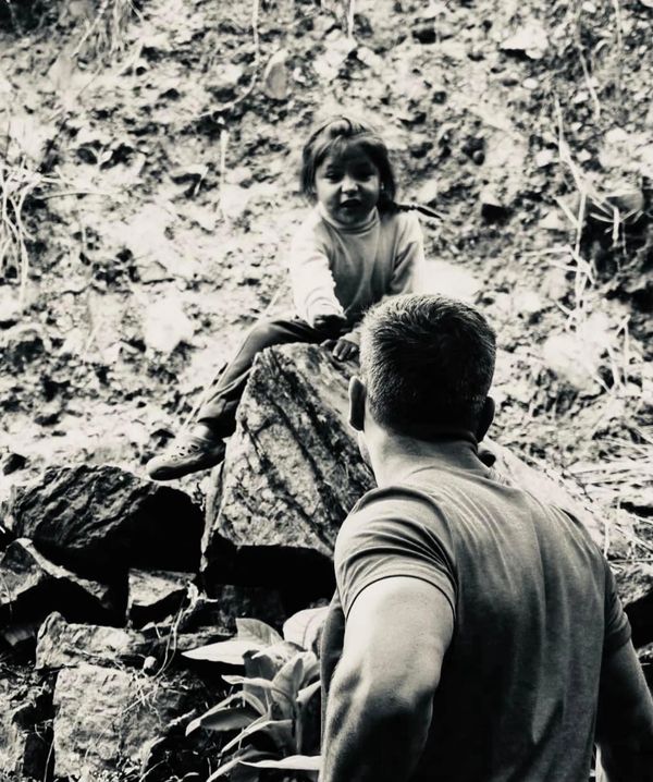 Man looking at a child seated on a rock.