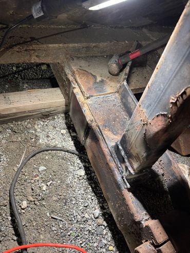 Rusty metal frame with a hammer resting inside.