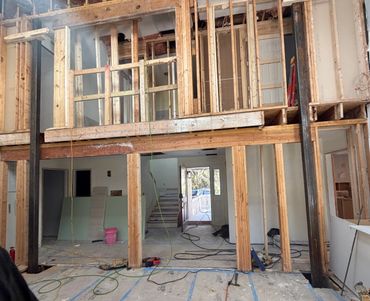 Interior of a house under renovation with exposed wooden framing and construction materials.