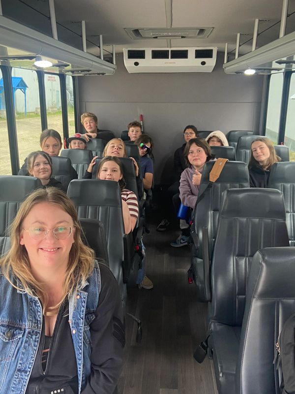 A group of children and an adult smiling inside a bus.