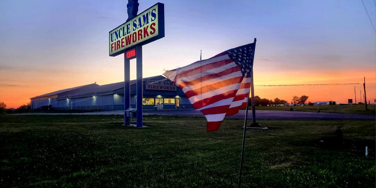 American flag waves outside Uncle Sam's Fireworks at sunset.