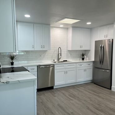 Modern white kitchen with stainless steel appliances and wood flooring.