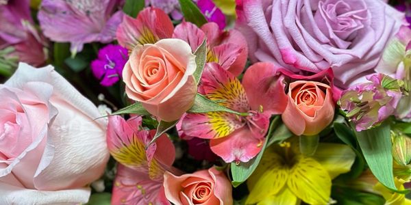 A vibrant bouquet of multicolored roses and lilies with lush greenery.
