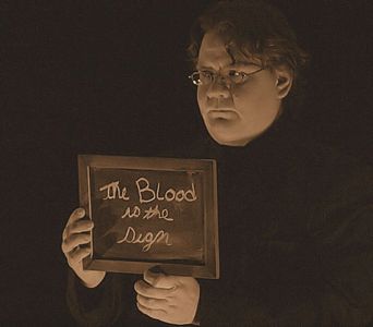 Man holding a sign that says 'The Blood is the Sign'.