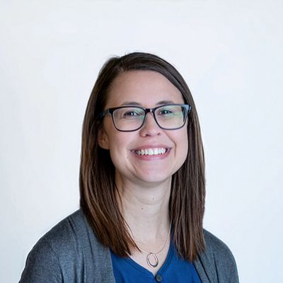 Smiling woman with glasses and straight brown hair.