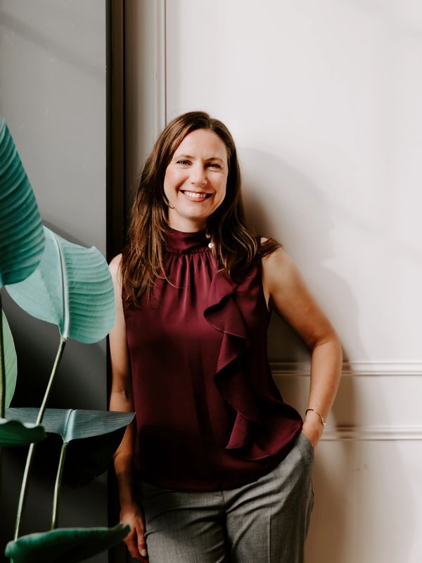 Woman standing and smiling next to a plant