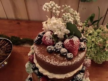A cake with fruits and flowers dusted with powdered sugar