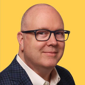 Smiling bald man with glasses in business attire.