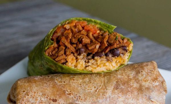 Two burritos on a plate, one cut in half.